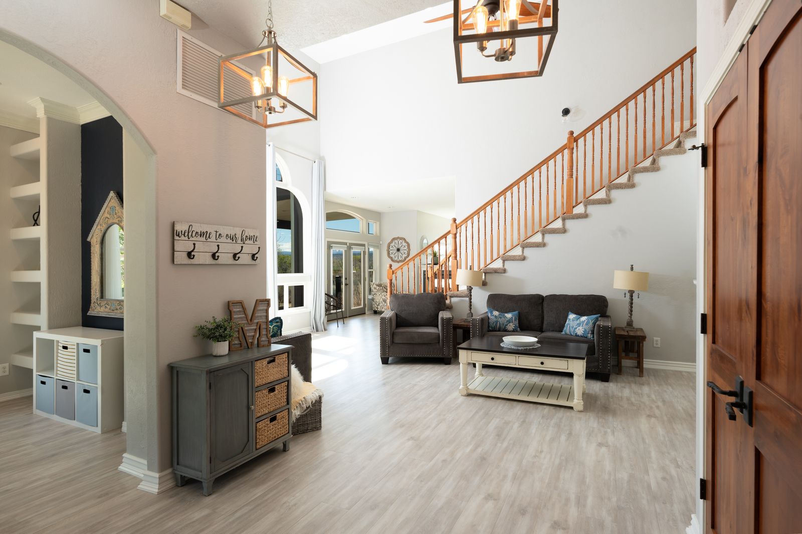 Open entryway with vaulted ceiling, cage pendant lights, staircase, and farmhouse decor