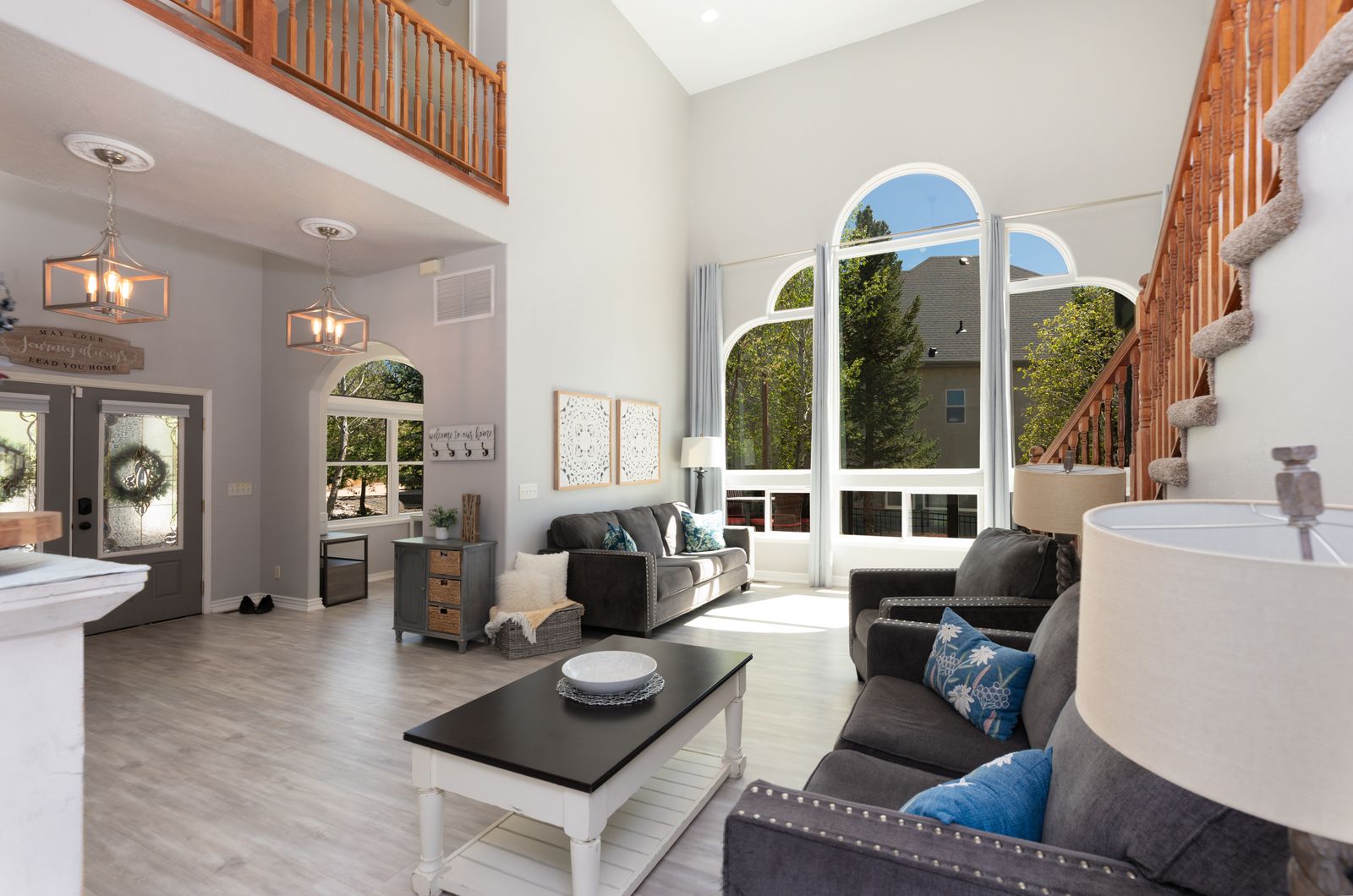 Two-story living room with arched windows, open loft, staircase, and natural light