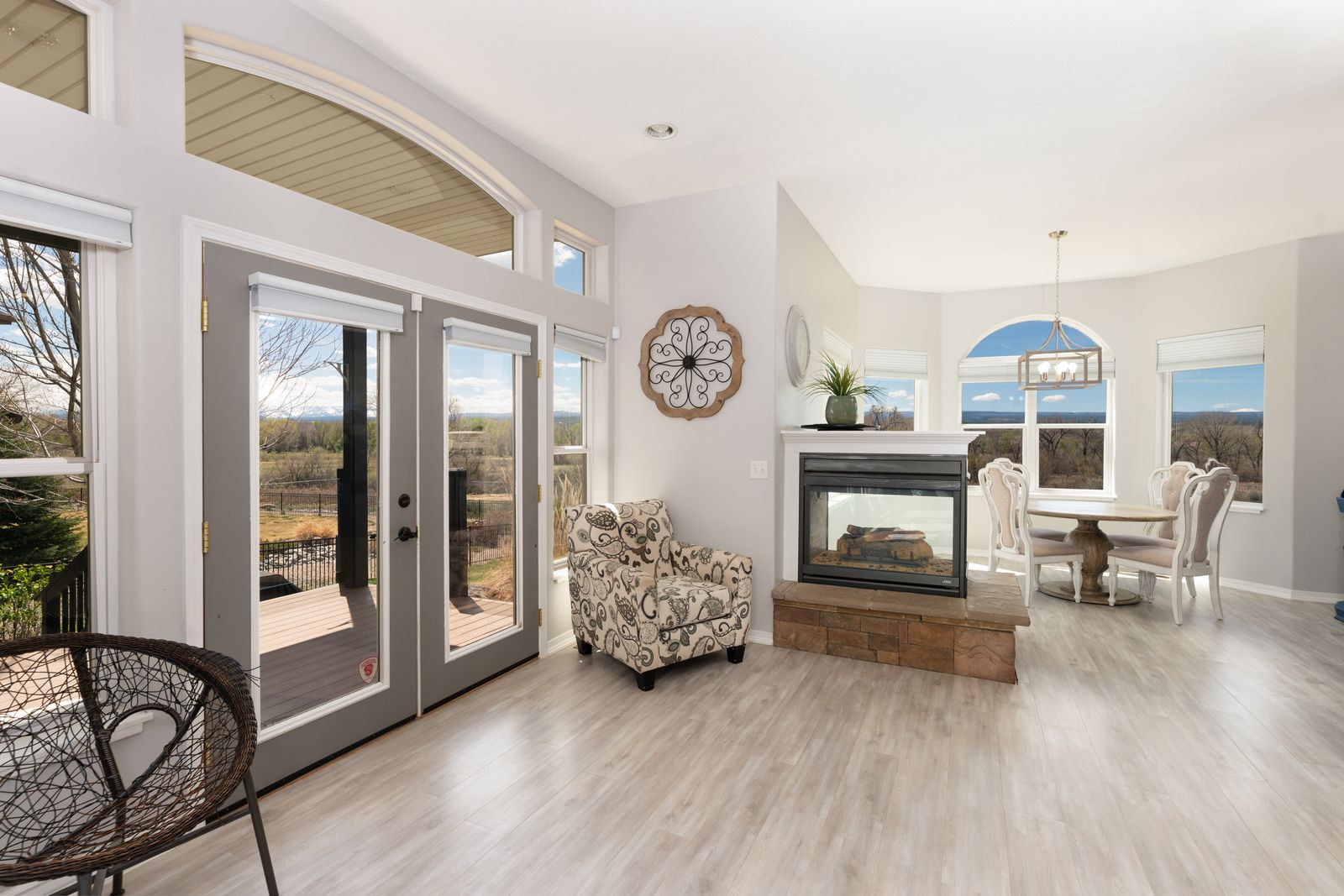 Sunlit sitting area with arched French doors, three-sided fireplace, and mountain views