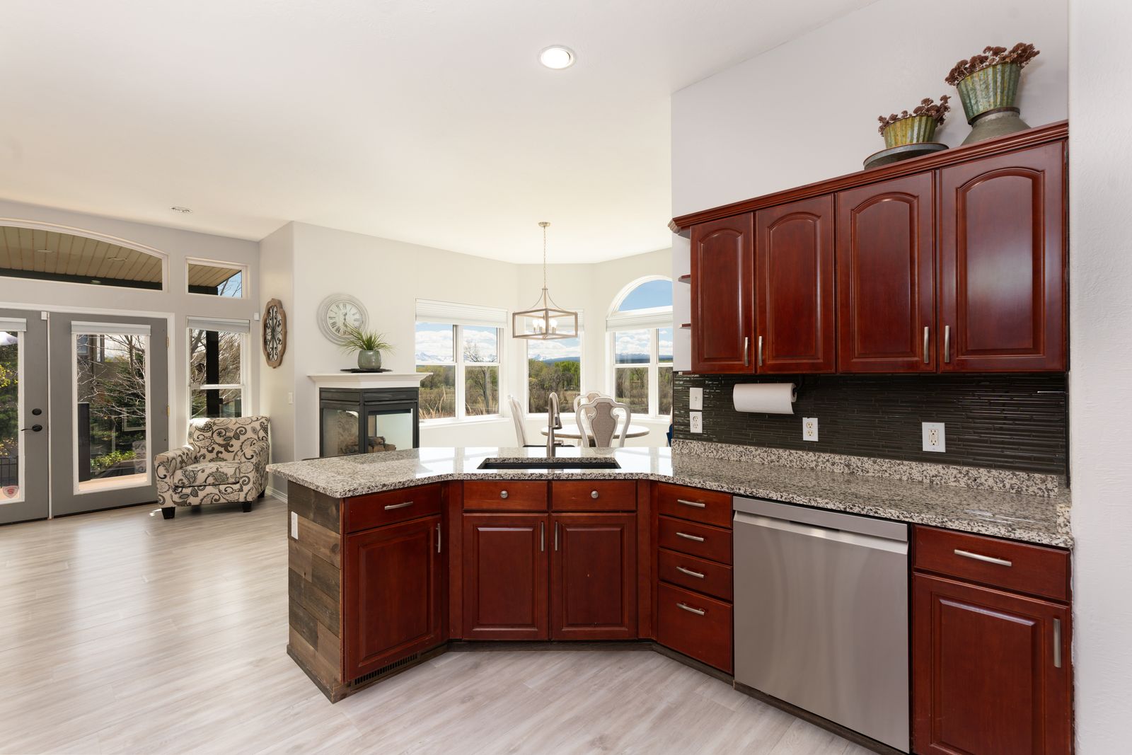 Kitchen with cherry cabinetry, granite countertops, and open view to fireplace and dining