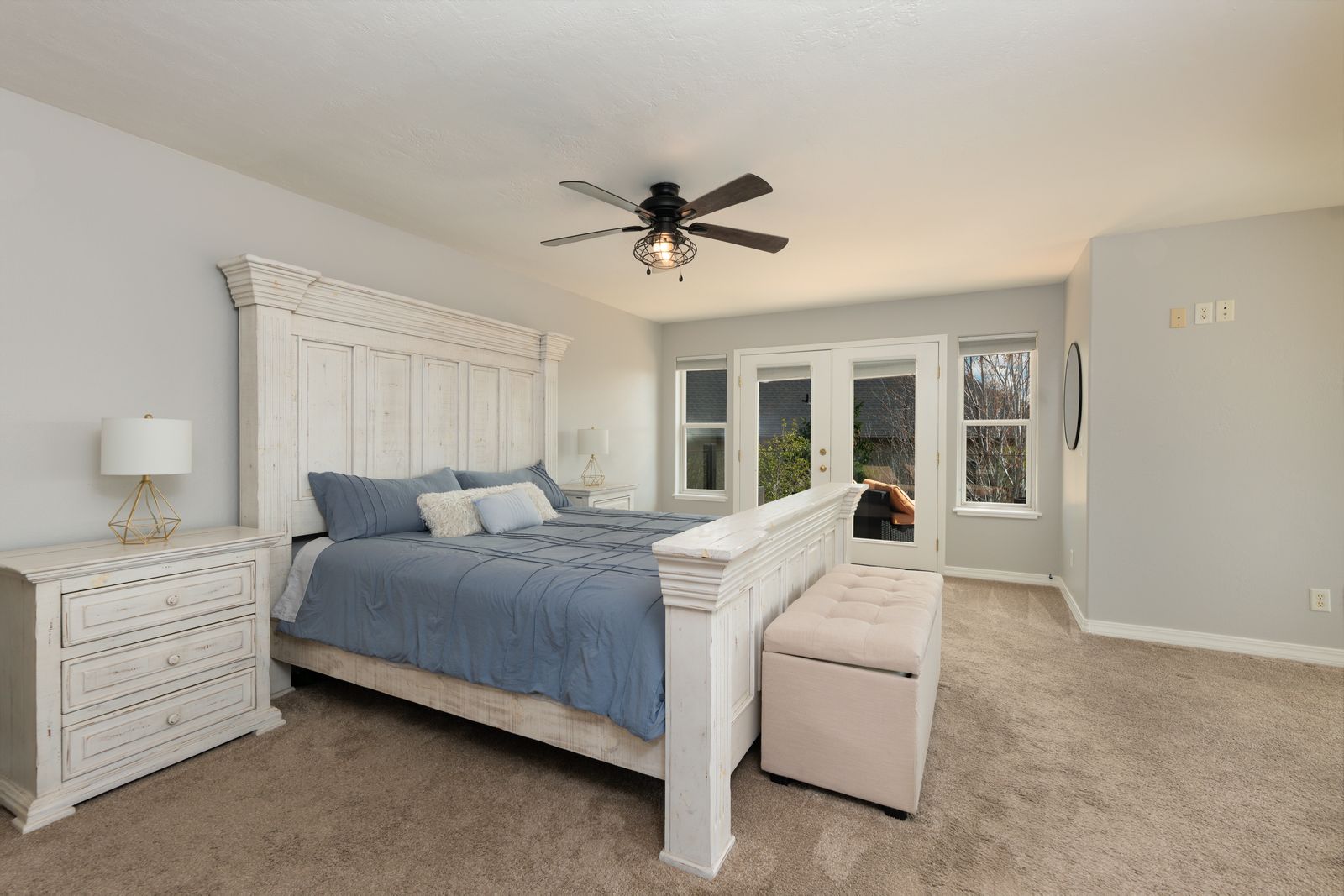 Primary bedroom with whitewashed wood bed frame, blue bedding, and ceiling fan