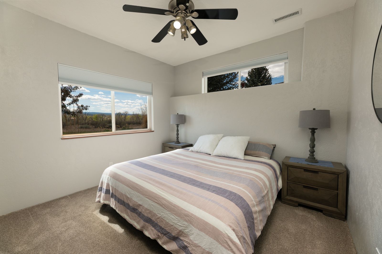 Guest bedroom with mountain views through corner windows and ceiling fan