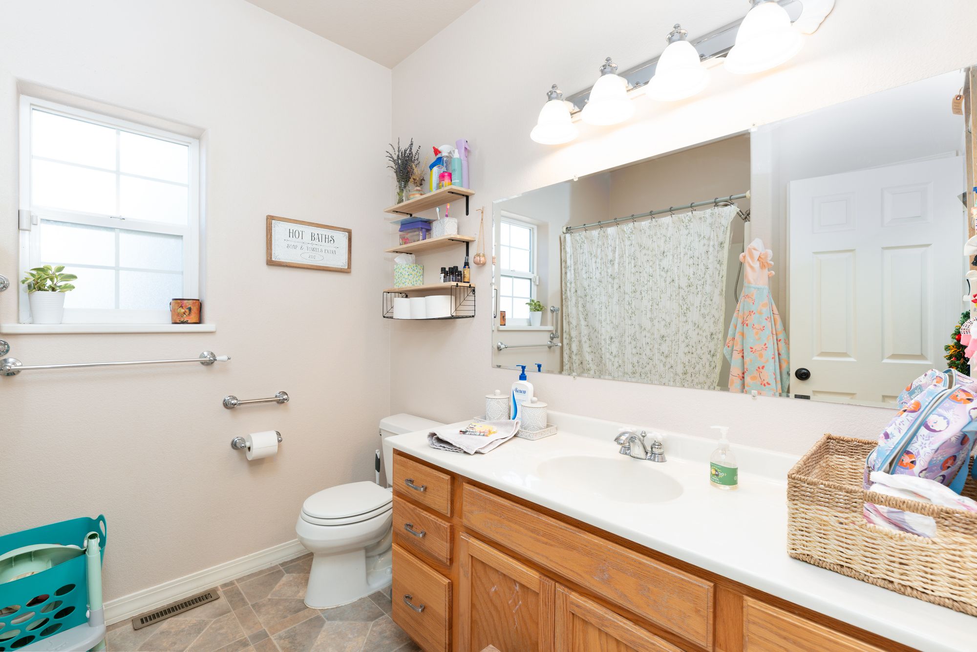 Bathroom with oak vanity, large mirror, and shower-tub combination