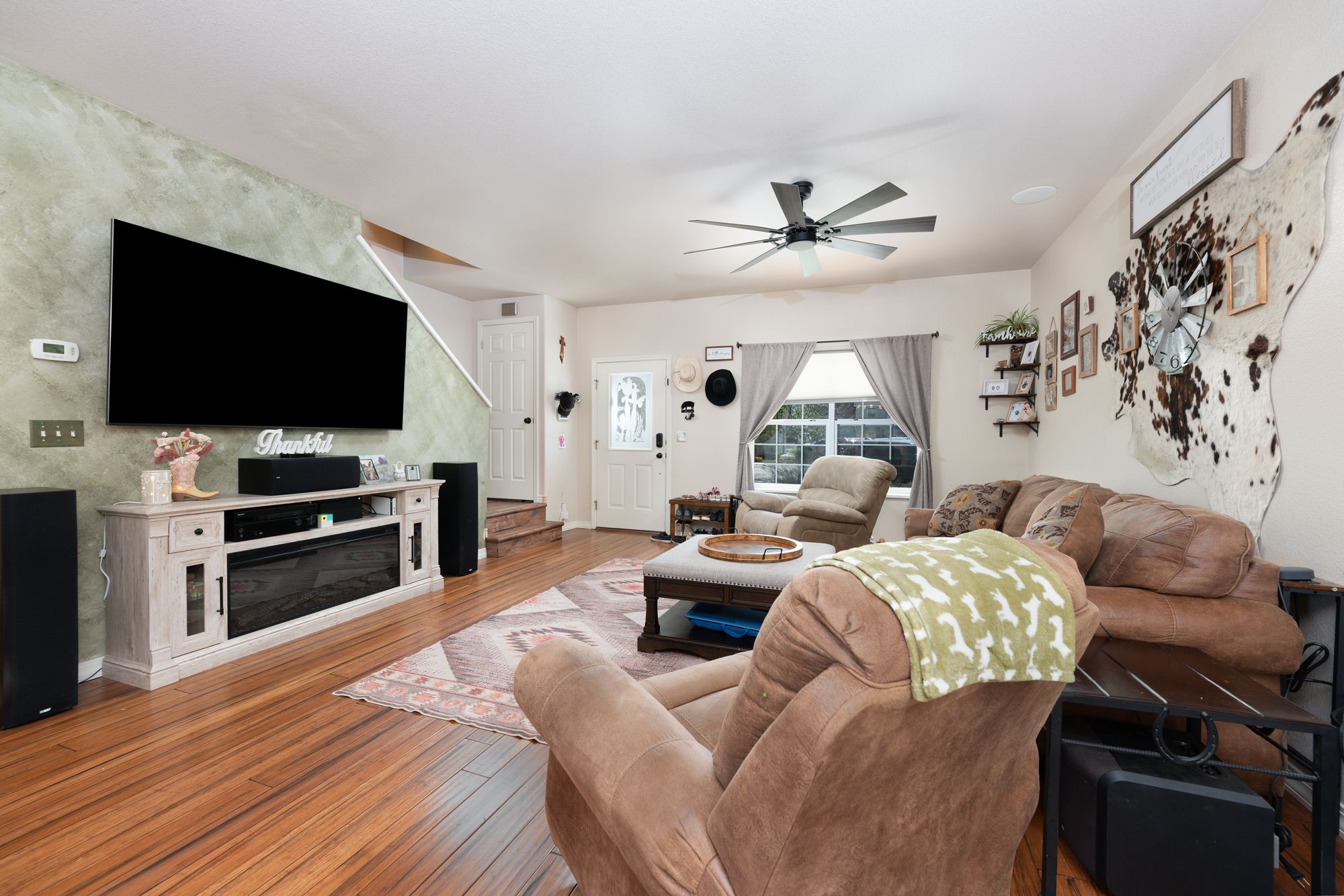 Living room with entertainment wall, accent textures, and hardwood floors