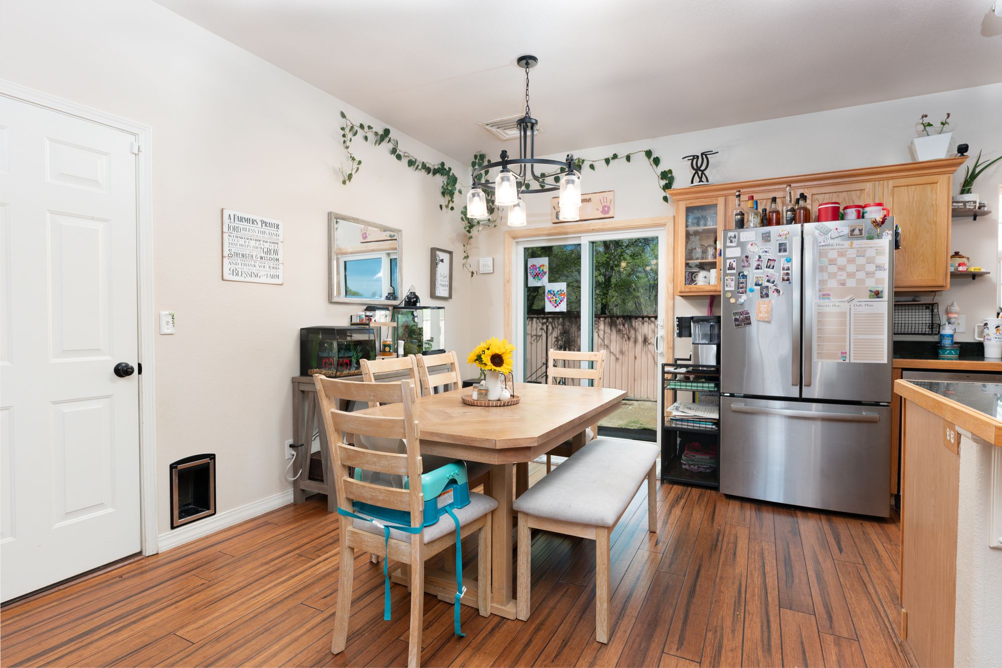 Dining area with sliding glass door, chandelier, and kitchen in background