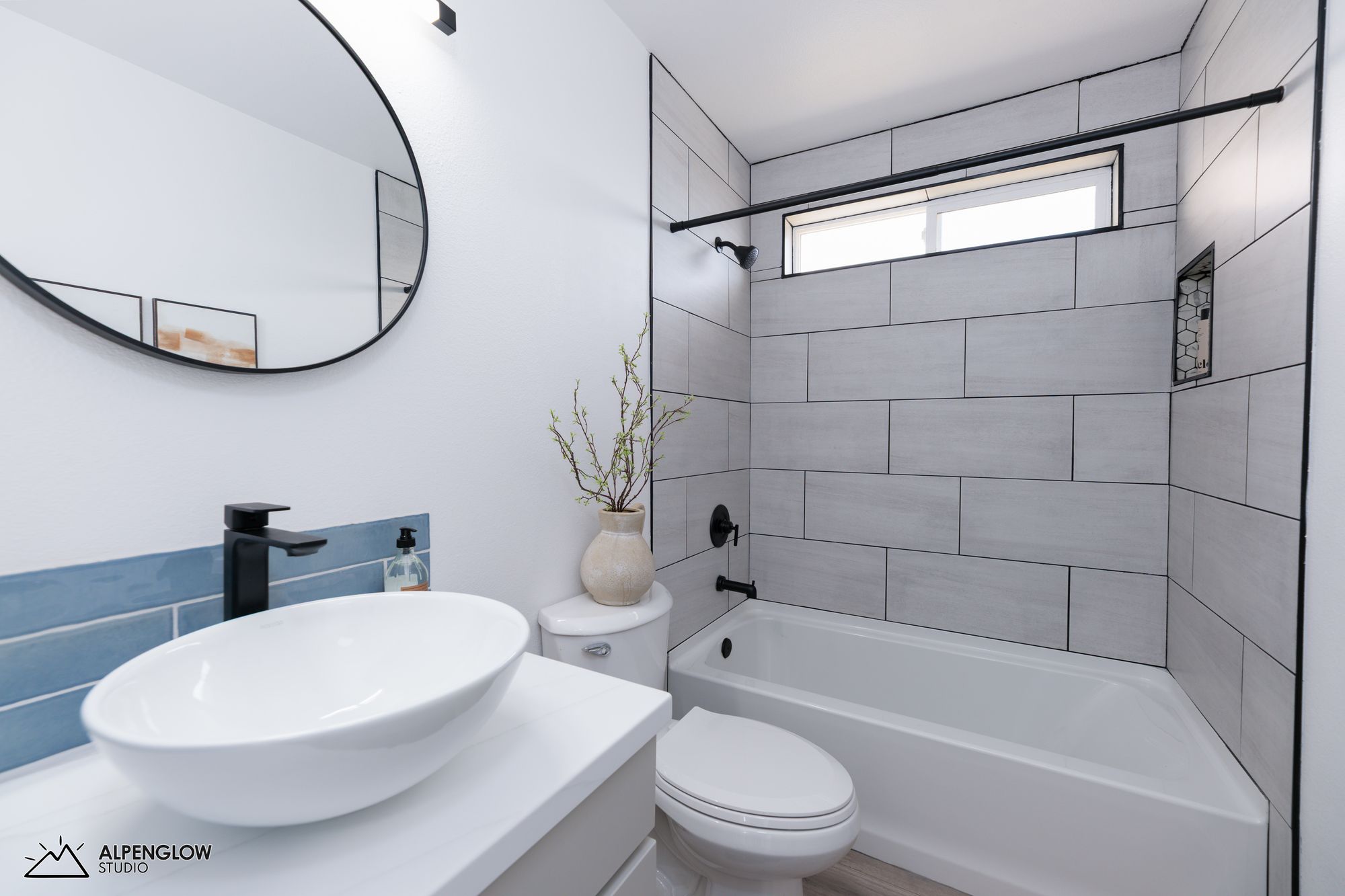 Bathroom with vessel sink, round mirror, and glass shower enclosure